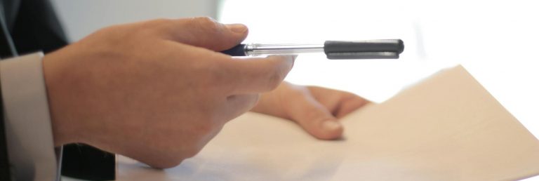 Close-up of a contract signing with hands over documents. Professional business interaction.